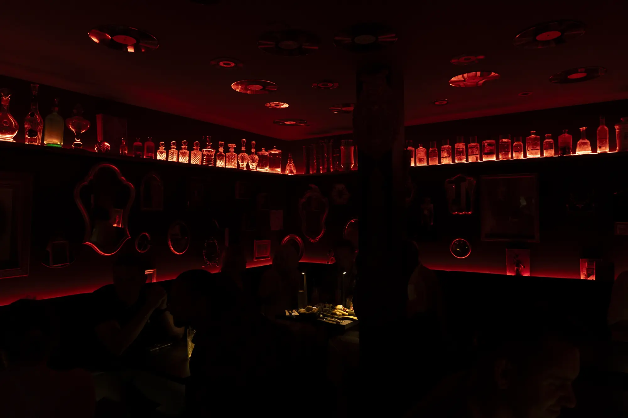 Le bar de La Crypte : bouteilles rétro-éclairées et lumière rouge sous les voûtes