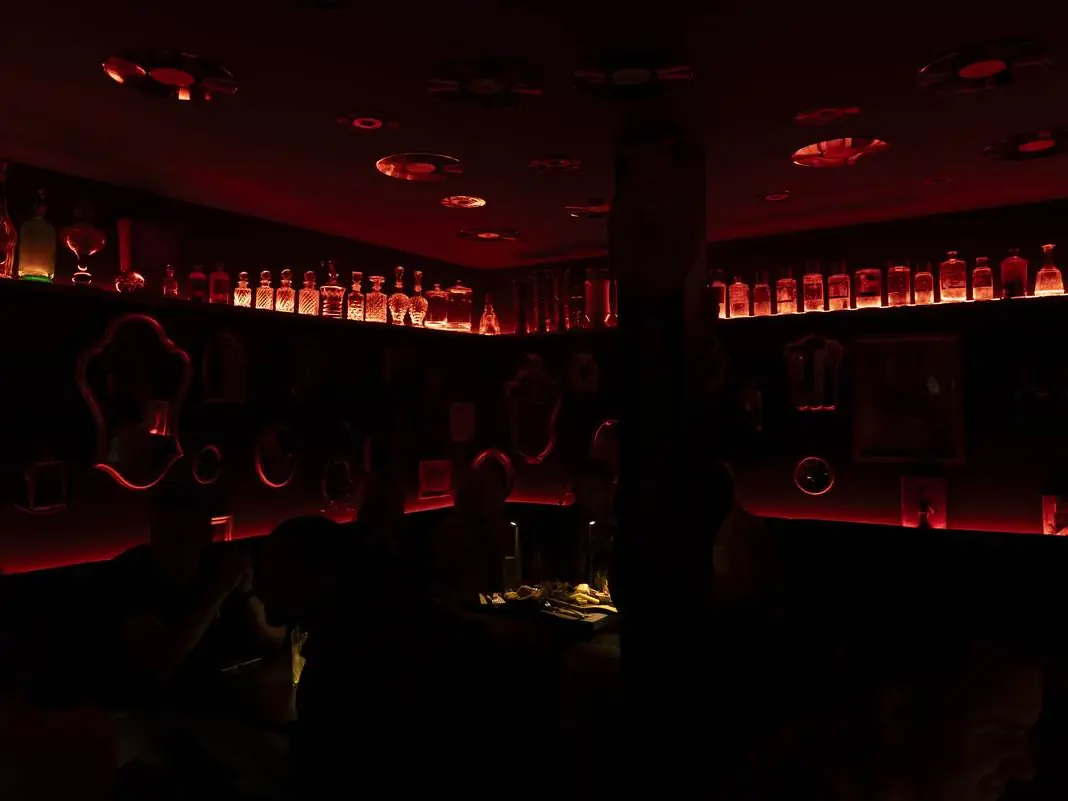 La Crypte, bar speakeasy sous L'Arche, lumière rouge et bouteilles rétro-éclairées