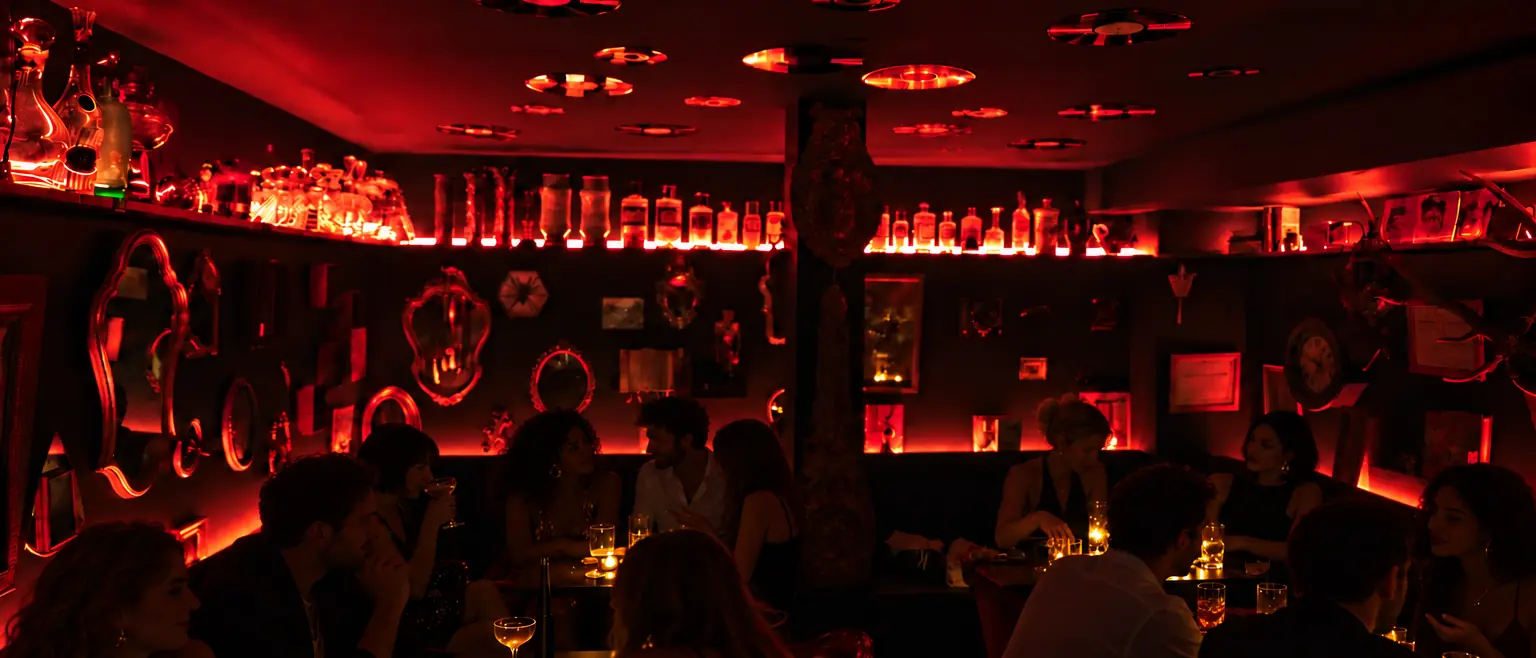 La Crypte, bar speakeasy de L'Arche : salle voûtée baignée de lumière rouge, miroirs et bouteilles rétro-éclairées